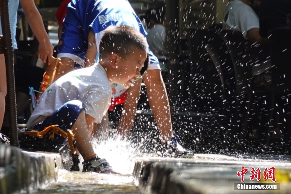 7月9日，陕西咸阳，小朋友在一民俗村的小水渠旁玩水。 中新社记者 张远 摄