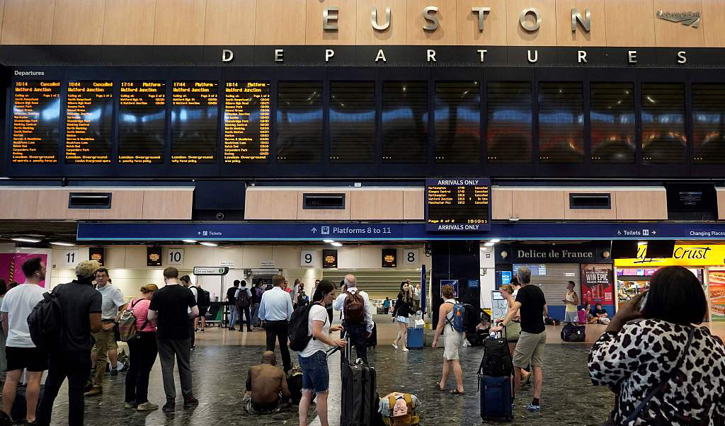 当地时间2022年7月19日，英国伦敦，市中心尤斯顿火车站旅客们看着空白的出发公告牌，由于铁轨边的火灾和英国经历的极端热浪，铁路服务被取消。